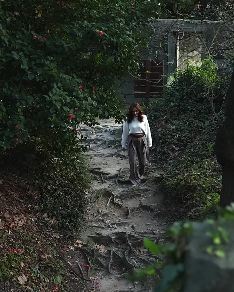 Mulher a descer escadas de pedra rodeadas de vegetação